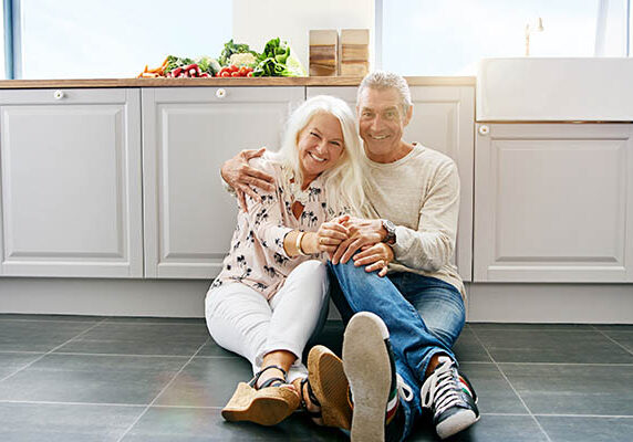 Happy couple sitting on Tile Floors | Kay Riley Flooring and Design