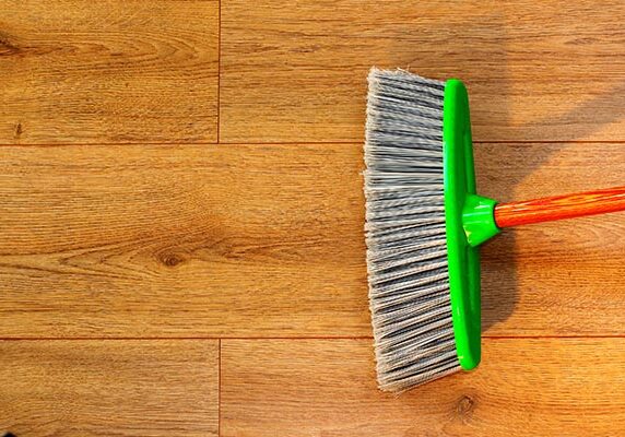Cleaning wooden floor with broom | Kay Riley Flooring and Design